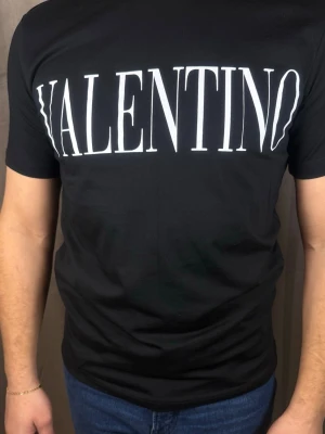 Svart Valentino t-shirt med logga - Snygg svart t-shirt från Valentino med stor vit logga över bröstet. Klassisk passform och rund halsringning. Perfekt för dig som gillar stilrena och trendiga plagg med statement-tryck.