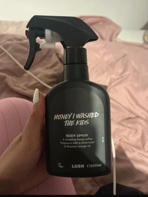 Lush Honey I Washed The Kids Body Spray - Provad endast 5 gånger! En svart sprayflaska med Lushs populära body spray 'Honey I Washed The Kids'. Doften är söt med toner av honung, kola och en fräsch twist av brasiliansk apelsinolja. Flaskan rymmer 200 ml och har en modern, stilren design.
