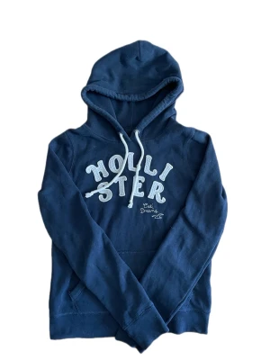 Hollister hoodie S - Säljer en riktigt mörkblå vintage hollister hoodie med broderad text. Tröjan är i storlek S. Tröjan har inga defekter - inga fläckar - inga hål - ingen dålig lukt ( kommer från djur och rökfritt hem🚭🐾) Tröjan är nyskick, då den knappt är använd✨🌟  Gåvor medföljer vid köp utan bud🎁💝  Tveka inte att ställa frågor vid minsta funderingar💬