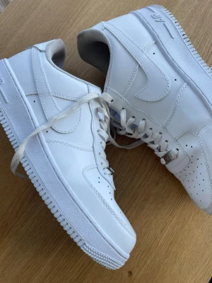 Nike Air Force 1 vita sneakers - Säljer ett par Nike Air Force 1 i vitt skick. Skorna är sparsamt använda och känns nästan som nya. Det finns lite creases (veck) på tån, men det är helt normalt och går enkelt att fixa eller förebygga med crease protectors.  Annars är de riktigt fräscha och sitter sjukt bra klassiska “feta” Nike Air som passar till allt 🔥 
