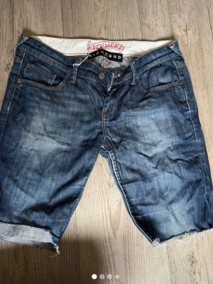 Blå jeansshorts från Richmond - Snygga blå jeansshorts från Richmond med  coola detaljer och broderier på bakfickorna. Klassisk femficksmodell med knappgylf och råa benslut som går att vika upp. Skit coola och snygga till sommaren!!!💕💕💕