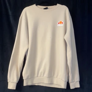 Beige sweatshirt från Ellesse - Säljer en snygg beige sweatshirt från Ellesse. Den har en klassisk rund halsringning och är långärmad. Tröjan är i bomull och har en liten Ellesse-logga på bröstet. Perfekt för en avslappnad stil!
