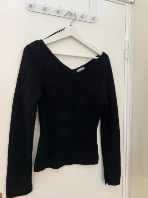 Svart stickad tröja med v-ringning H&M - Svart stickad tröja från H&M med snygg v-ringning och långärmad design. Tröjan är figurnära och har en enkel, stilren look som passar perfekt till jeans eller kjol. Materialet är mjukt och bekvämt, perfekt för att hålla dig varm under kyliga dagar.