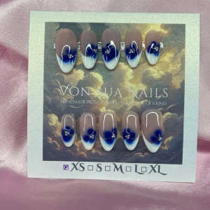 Sthlm (XS);Medium Almond - Snygga handgjorda press-on naglar i en medium lång mandelform. Naglarna har en nude bas med blå blommor på tippen och vita french samt silverfärgade dekorationer. Perfekt för dig som vill ha en unik och trendig look.XS: 14 mm, 11 mm, 11,5 mm, 10 mm, 8 mm 