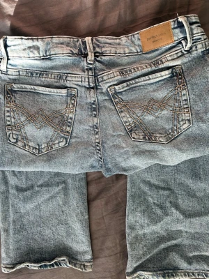 Ljusblå bootcut jeans från Gina - Ljusblå bootcut jeans med snygga broderade bakfickor och klassisk femficksdesign. Jeansen har en tvättad look och raka ben med lätt utsvängning. Perfekta för en avslappnad och trendig stil. 