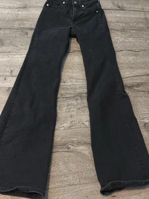 Svarta utsvängda jeans - Snygga svarta jeans med utsvängda ben och klassisk femficksmodell. Jeansen har hög midja och är tillverkade i denim med lite stretch. Perfekta för dig som gillar en retroinspirerad look med mycket attityd.