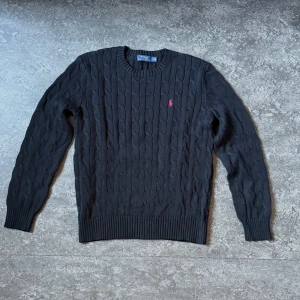 Polo Ralph Lauren Kabelstickad tröja - Tjena! Säljer en stilren svart kabelstickad tröja från Polo Ralph Lauren. Mycket bra skick, i princip är den helt ny då den aldrig kom till användning. Passar formella eller avslappnade outfits. Säljer för endast 499kr, köpt från Zalando för 2395kr. Inga skambud. Hör av er vid funderingar 🙌.