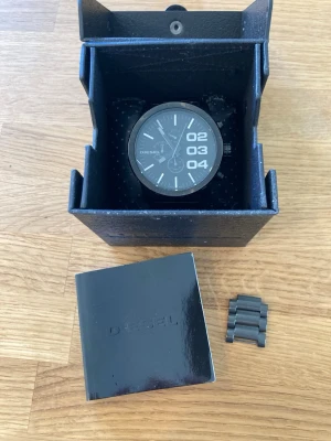Diesel Chrono DZ-4207 52mm Herrklocka - Säljer en Diesel Chronograph herrklocka, modell DZ-4207. Nyskick enligt bilder med en tunn repa i glaset (kan nog poleras bort). Klockan har ett quartzurverk och en svart urtavla med tydliga markeringar. Boetten och armbandet är i svartfärgat rostfritt stål. Klockan är vattentålig upp till 5 BAR. Extra länkar och manual medföljer samt Diesel originalbox. Behöver bara nytt batteri.  Nypris: 2500 SEK Begagnat värde: < 1000 SEK Mitt pris: 589 SEK  Skickas snabbt och spårbart. Skriv vid frågor och s