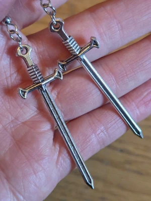 Örhängen med svärd goth punk - Silvriga örhängen med svärd. Ca 7.5 cm långa. Material: zinklegering.