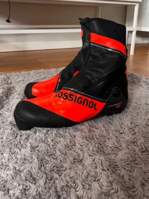 Rossignol - X-ium Carbon Premium+ Classic - Snygga klassiska längdpjäxor från rossignol i strl 42 i nyskick!  Använda två gånger under prov men är något trånga i hälen för han som köpte dom.  Nypris 5.500kr  Strl: 42 Färg: Svart/röd  Skick: Nyskick (finns en liiiten repa på ena skons undersida. Se bild)  Modell: Rossignol - X-ium Carbon Premium+ Classic Övrigt:  - Kolfiber förstärkt chassi som utlovar stabilitet.  - Sula i kolfiber som ger bra fotrullning  - Smidig och anatomisk passform som lämpar sig utmärkt i både träning och tävling 