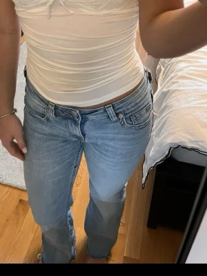 Ljusblå raka jeans från H&M - Säljer ett par ljusblå jeans från  H&M  med klassisk femficksmodell och raka ben. Jeansen har låg midja och subtila slitningar för en avslappnad look. Perfekta till en trendig vardagsstil.