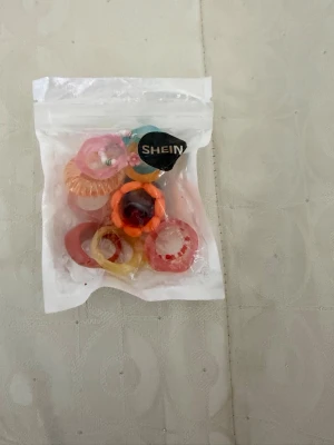 Färgglada ringar från SHEIN - Ett paket med flera färgglada ringar från SHEIN. Ringar kommer i olika former och färger som rosa, orange, röd, gul och blå. Tillverkade i elastiskt material.