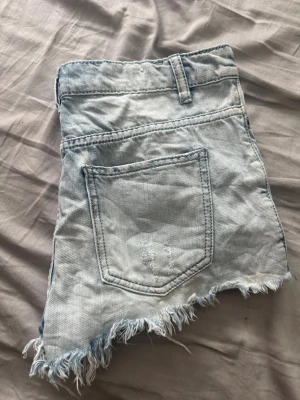 Ljusa jeansshorts med fransig kant - Säljer ett par ljusblå jeansshorts dom är jättefina skulle jag säga knappt använda då dom var lite för små stolek S/M 💕 inget fel på dom. Vet dom inte vart dom är i från men det står på lappen på bilden 