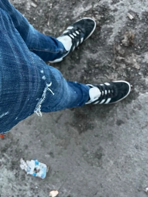 Mörkblå slitna skinny jeans - Säljer ett par mörkblå Disqaurd2 jeans med slitningar och trasiga detaljer vid knät. Jeansen har en klassisk femficksmodell och är tillverkade i stretchigt denimtyg för en tajt passform. Perfekta för en avslappnad och trendig look. GE PRISFÖRSLAG