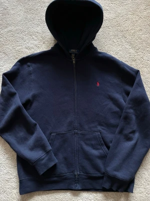 Marinblå hoodie från Polo Ralph Lauren - Säljer denna mycket snygga mörk blå hoodie från Ralph Lauren den är perfekt för en stilren och avslappnad look till vardags! Enbart använd 2-3 gånger