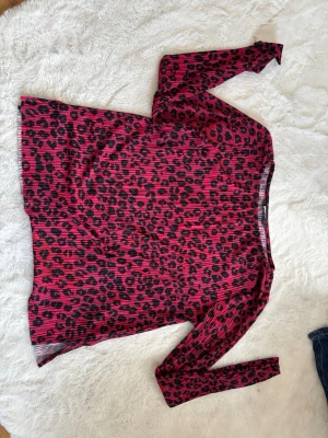 Leopardmönstrad topp från Gina Tricot - Säljer en långärmad topp från Gina Tricot i stark rosa med svart leopardmönster. Toppen är ribbad och har en figurnära passform. Perfekt för dig som vill sticka ut med ett djurmönstrat plagg!använts ett ex antal gånger men ingen skada vad jag ser, pris kan diskuteras.