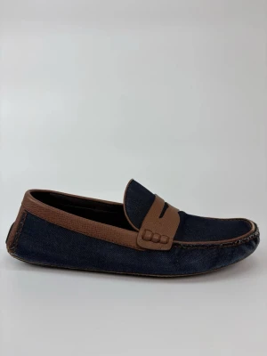 Mörkblå Louis Vuitton loafers med bruna detaljer - Snygga loafers i mörkblått tyg med bruna detaljer och klassisk penny strap. Skorna har en stilren design med kontrastsömmar och rundad tå. Perfekta för dig som gillar en avslappnad men ändå trendig look.