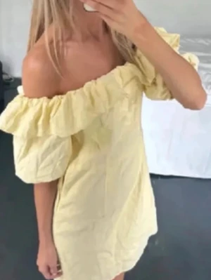 Gul offshoulder klänning med volang - Söt gul kortklänning med offshoulder-modell och stora volangdetaljer runt axlarna. 