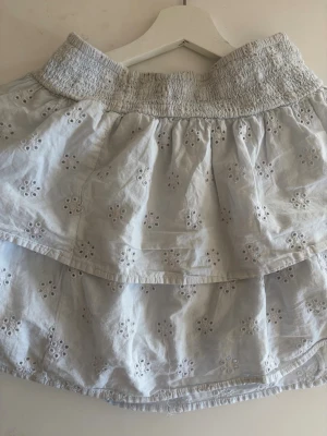Vit volangkjol med broderade detaljer  - Söt vit kortkjol med volanger och broderade blommönster. Den är från Gina och är i storlek S. 