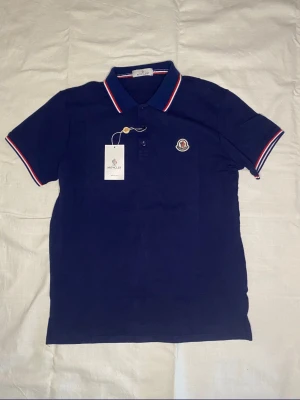 Marinblå pikétröja från Moncler - Säljer en mycket fin piké, perfekt nu till sommaren! Säljes för 349:- styck finns 2 i varje färg:) (BÅDA SVARTA ÄR SÅLDA) vid frågor så är det bara att höra av sig ! 