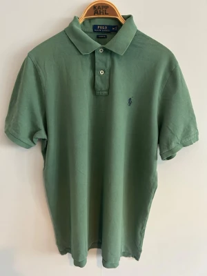 Grön pikétröja från Polo Ralph Lauren - • 🇸🇪 Mörkgrön Piké från Polo Ralph Lauren. Broderad logga på bröstet.   Använd, men fortfarande i fräscht skick utan några speciella anmärkningar.   Pris går alltid att diskutera vid snabb affär 🥂  