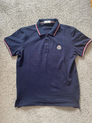 Marinblå pikétröja från Moncler - Säljer en mycket fin piké, perfekt nu till sommaren! Säljes för 349:- finns endast 2 kvar i denna färg:) (BÅDA SVARTA ÄR SÅLD) vid frågor så är det bara att höra av sig ! 