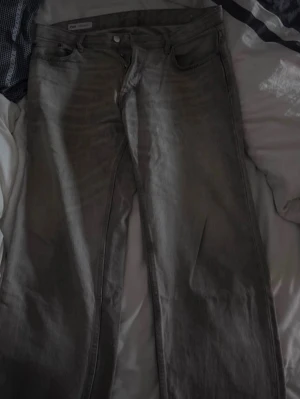 Grå raka jeans från Zara - Säljer ett par grå jeans från Zara med rak passform och klassisk femficksdesign. Jeansen har knapp- och dragkedjegylf samt bälteshällor. Perfekta för en avslappnad och stilren look.