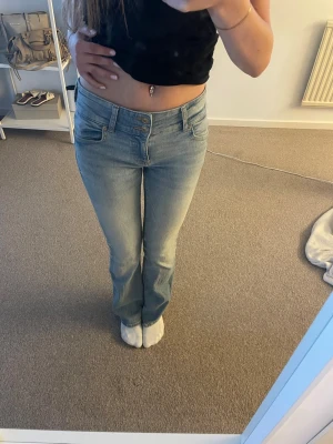 Ljusblå bootcut jeans med hög midja - Säljer ett par ljusblå bootcut jeans med hög midja. Jeansen har en snygg tvätt och stängs med knapp och dragkedja. Perfekta för dig som gillar en avslappnad men trendig look. Går även att vika ner och göra lågmidjad!