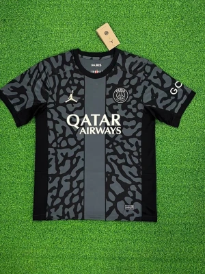 PSG Jordan svart vitt grå helt ny! M size  - Svart PSG tröja Jordan med grått/ svartmönster fram och bak. Har en grå rand på framsidan och vit text. Aldrig använd och i verkligen fint skick.”
