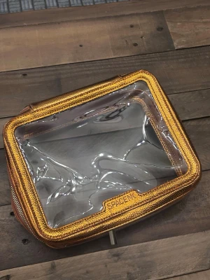 Transparent necessär med guldkant från Space NK - Snygg och praktisk necessär från Space NK med transparent plast och glittrig guldkant. Perfekt för att organisera smink eller skönhetsprodukter. Fyrkantig form med dragkedja runt om och tydlig insyn så du snabbt hittar det du behöver. Det är den största varianten 🤩