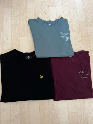 3-pack från Lyle & Scott och 157 - Säljer tre snygga plagg en svart sweatshirt från Lyle & Scott med gul logga, en vinröd och en blågrå från 157 med vit text och tryck. Alla har rund hals, perfekta till jeans eller shorts. Materialet är mjuk bomull som känns skönt mot huden.