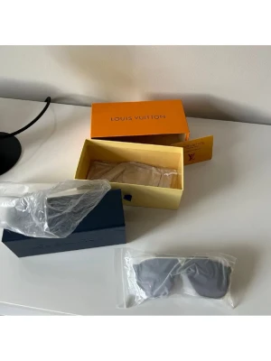 Säljer ett par svarta solglasögon  - Säljer ett par svarta solglasögon från Louis Vuitton med klassisk, stilren design. Glasögonen har breda bågar och mörka glas, levereras med originalbox och tillbehör. Perfekta för dig som vill ha en lyxig och trendig accessoar.