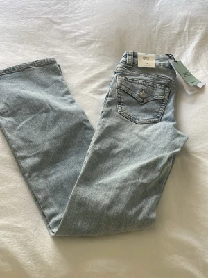 Ljusblå bootcut jeans från Gina Tricot Tall - Snygga ljusblå bootcut jeans från Gina Tricot med klassisk femficksdesign och en liten ficka med lock bak. Jeansen har utsvängda ben och är gjorda i mjuk denim med en lätt tvättad look. Perfekta för en trendig och avslappnad stil.