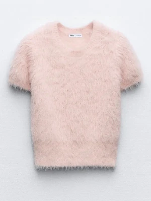 Ljusrosa fluffig stickad tröja Zara - Supersöt ljusrosa stickad tröja från Zara med korta ärmar och rund hals. Tröjan är gjord i ett fluffigt, mjukt material som ger en trendig och mysig look. Perfekt att styla med jeans eller kjol för en cool vibe.