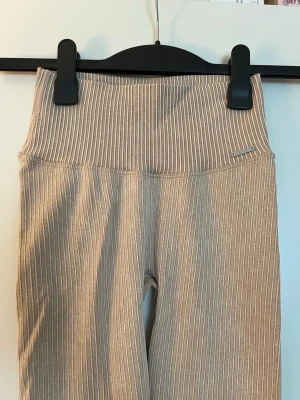 Beige ribbade leggings Aim'n XS - Beiga ribbade tights från Aim'n i storlek XS. Tightsen är gjorda i ett stretchigt material av 92% polyamid och 8% elastan. Perfekta för träning eller chill dagar. Helt nya, aldrig använda! 
