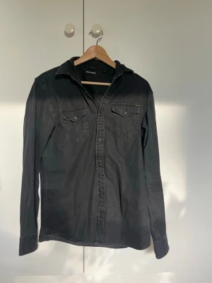 Svart skjorta från Jack & Jones - Klassisk svart skjorta från Jack & Jones med två bröstfickor och knappar framtill. Skjortan har lång ärm och en avslappnad passform, perfekt till jeans eller chinos. Tillverkad i mjuk bomull för en bekväm känsla.