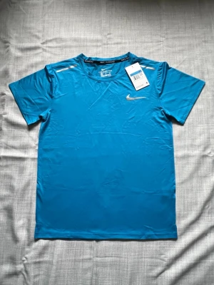 Nike miler T-shirt blå strl M - Säljer en helt ny Nike T-shirt i blå färg. Väldigt clean modell och perfekt till sommaren. Enkel att matcha och passar till allt. Oanvänd i storlek M. 