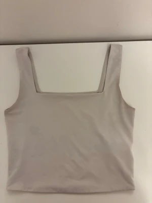  linnetopp  - Säljer en stilren vit linnetopp med breda axelband och fyrkantig urringning. Toppen är ärmlös och har en croppad passform som passar perfekt till både jeans och kjol. Materialet känns mjukt och stretchigt, vilket gör den superbekväm. Kan ha lite fläckar när jag har tvättat den.