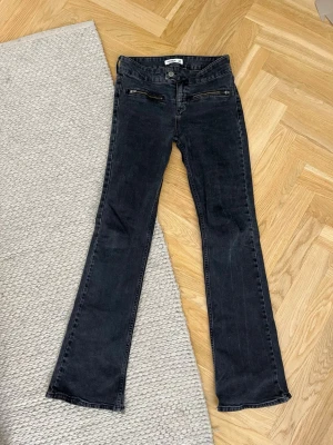 Svarta bootcut jeans med dragkedjor - Snygga svarta bootcut jeans med dragkedjor framtill och klassisk knappstängning. Jeansen har en lätt tvättad look och raka ben som går ut lite nertill.