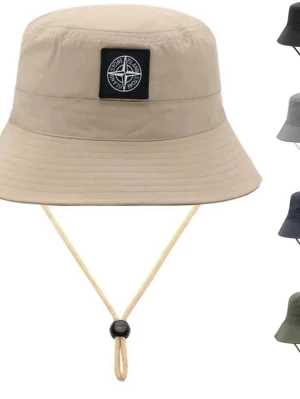 Beige bucket hat från Stone Island - Stilren beige bucket hat från Stone Island med klassisk logopatch framtill. Hatten har justerbar hakrem och är tillverkad i lätt, slitstarkt material som passar perfekt för soliga dagar. Insidan har vita detaljer och etiketter med varumärkesinfo.