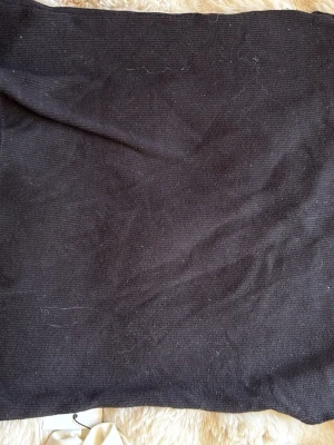 Svart ribbad tubtopp från H&M Divided - En svart ribbad tubtopp från H&M Divided i storlek XS. Toppen är axelbandslös och har en enkel, tight passform med diskret spetskant upptill. Perfekt att styla med jeans eller kjol för en clean look.