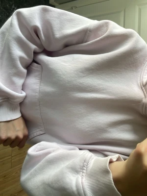 Ljusrosa hoodie med huva - En stilren ljusrosa hoodie med huva och magficka. Tröjan har ribbade muddar vid ärmslut och nederkant. Tillverkad i mjukt sweatshirtmaterial som känns skönt mot huden. Perfekt för dig som gillar en enkel och clean look.