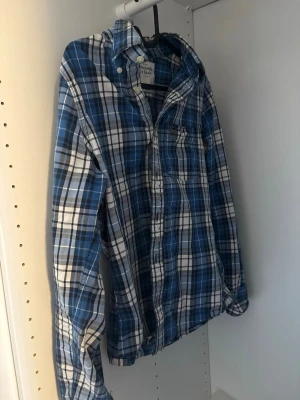 Blårutig skjorta från Abercrombie and fitch - Snygg blårutig skjorta med klassisk krage och långa ärmar. Skjortan har knäppning framtill och en bröstficka. Perfekt för en avslappnad och cool stil. Archive