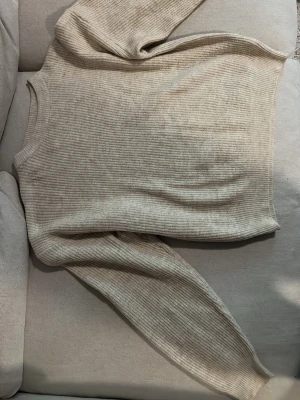 Beige stickad tröja från Firefly - Säljer en beige stickad tröja från Firefly med rund halsringning och ribbade muddar. Tröjan har en enkel, stilren design och är gjord i mjukt, ribbstickat material. Perfekt för lager på lager och passar till det mesta.