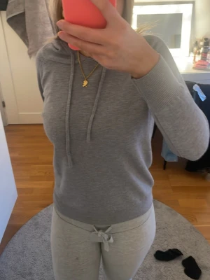 Ljusgrå hoodie - Säljer en enkel och stilren ljusgrå hoodie med huva. Hoodien har långa ärmar och ribbade muddar vid ärmslut och nederkant. Perfekt för en avslappnad look och passar till det mesta. Materialet känns mjukt och bekvämt.