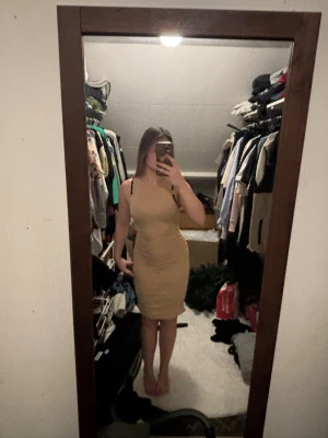 Beige ribbad kort klänning - Säljer en beige ribbad klänning med tight passform och ärmlös design. Klänningen är kort och har en enkel, stilren look som framhäver figuren. Perfekt för dig som gillar minimalistisk stil och vill ha något bekvämt och snyggt.