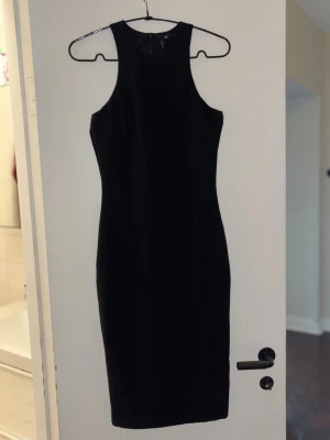 Svart ärmlös klänning - Snygg svart ärmlös klänning från H&M med figurnära passform. Klänningen har en stilren design och dragkedja i ryggen. Perfekt för dig som gillar minimalistisk och klassisk stil.