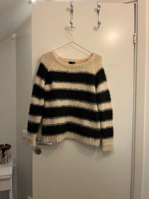 Randig stickad tröja i svart och beige - Säljer en jätte skön stickad tröja, har använt typ två gånger och tröjan är i ett bra skick inga hål eller skador.