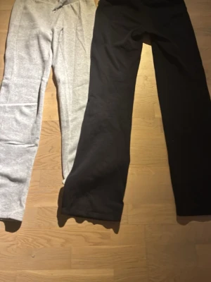Gråa och svarta mjukisbyxor med snörning - Två par mjukisbyxor, ett par i ljusgrått och ett par i svart. Båda har bred mudd i midjan och snörning för justerbar passform. Skit snygga och låg midjade från HM, är för små för mig💕