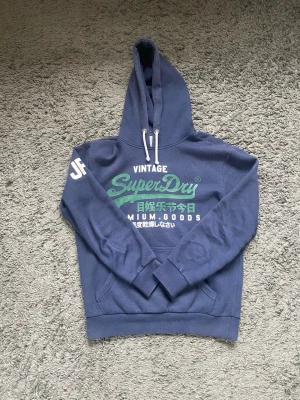 Superdry hoodie - Tja!😁 Säljer nu denna superdry hoodien i storlek M då den har blivit för liten för mig. Hoodien är i mycket bra skick utan hål eller defekter någonstans. Hör av er om ni har några frågor om hoodien eller priset.🤝